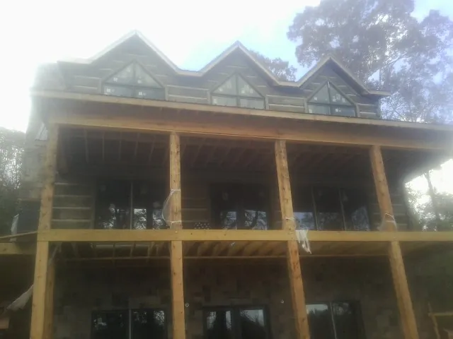 Dormers and porch framing on a large log home under construction — Roof Coating work by our crew in Vernon